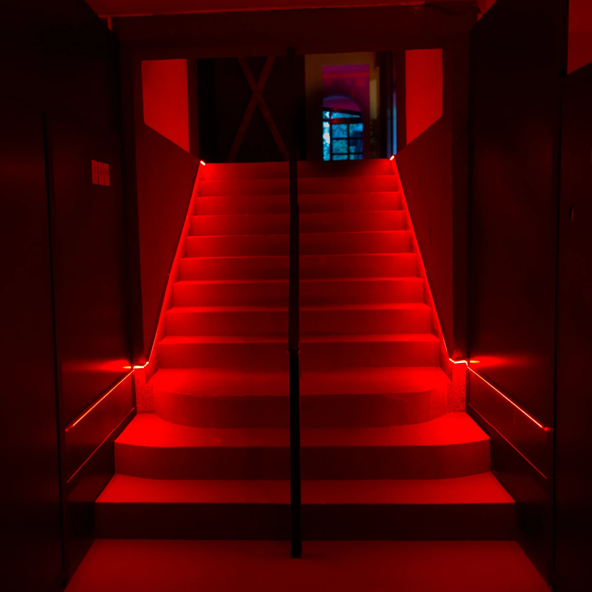 Červeně osvětlené schodiště vedoucí do vnitřní lounge